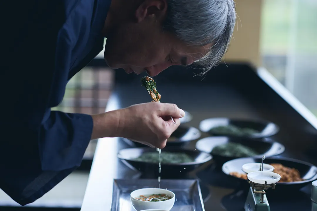 このお茶をお届けするのは、2026年に創業100年を迎える株式会社宇治田原製茶場です。緑茶発祥の地として知られる京都・宇治田原町の地で、長い歴史と共に日本茶文化を支えてきたお茶屋がお届けする玄米茶専門ブランド「京玄米茶 上ル入ル」。


なぜ今、あえて玄米茶なのか。
それは、昭和初期に京都の茶商が、鏡開きで割れた鏡餅のかけらを「無駄にしたくない」と炒って茶葉に混ぜたことが始まりとされる、玄米茶の原点をもう一度見つめ直すため（諸説あり）。縁起物を最後まで大切にする「始末の文化」に宿る暮らしの知恵を、現代の私たちがもう一度思い出し、共有したいと考えました。


一般的な玄米茶は炒り米を使用しますが、ルーツである「炒り餅」に立ち返り、京都の老舗米菓舗「鳴海屋」の職人が備長炭の炭火で香ばしく炒ったお餅を、選び抜かれたお茶とブレンド。製法から品質管理まで徹底し、100年続く茶づくりの知恵を、美味しさと共に安心・安全と一緒にお届けします。


ブランド名の「上ル入ル」は、京都独特の住所表記から着想を得た言葉です。
京のまちを歩くように少し先へ進む、暮らしに縁起の良い気を「上げる」―そんな意味を込めています。一杯のお茶で心をほっと整え、気分を少し「上ル」。


玄米茶の始まりに込められた縁起の良さと、暮らしの知恵をもう一度現代へ。
「京玄米茶 上ル入ル」は、伝統に立ち返りながらも、常識に縛られない新しいお茶のかたちをお届けします。
