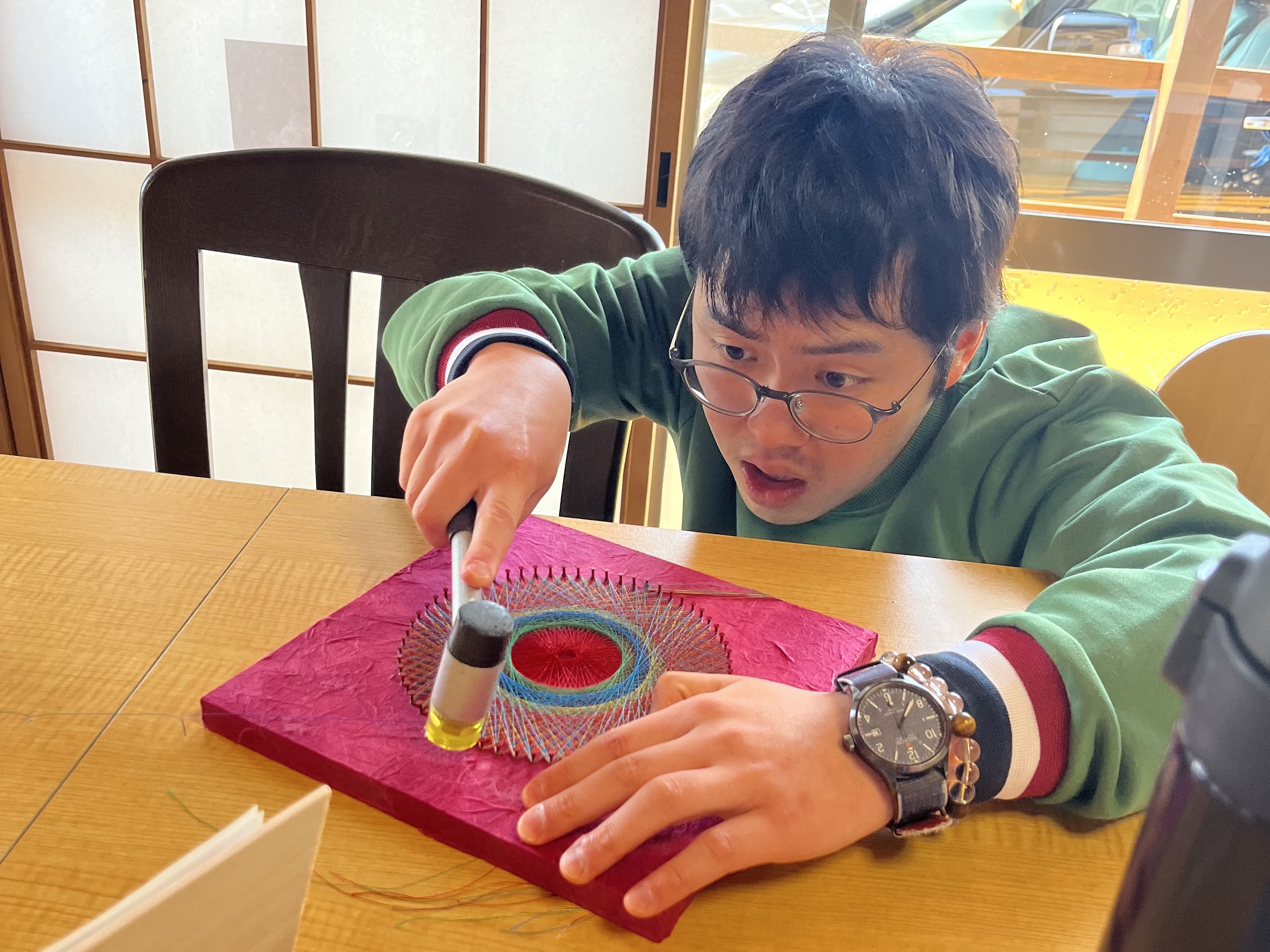 この商品を手がけたのは、「やまとあい」を利用する糸かけ職人、星 佳佑（ほし けいすけ）さんです。

作品のサイズは職員がアドバイスしますが、色合いや糸の掛け方は星さん自身が決めるという強いこだわりがあります。その集中力と個性が生み出した、唯一無二の曼荼羅アートです。

星さんは一閑張りの制作を通じて「これは僕の作品です」と自らの口で言えるほどの大きな自信をつけました。

完成：令和7年5月